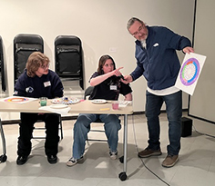 man holding a painting as two people look at the painting