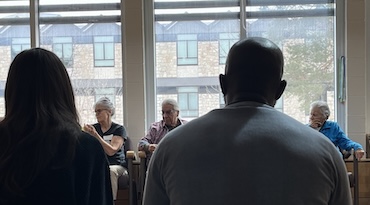 looking over the shoulders of two people seeing three people sitting near a window